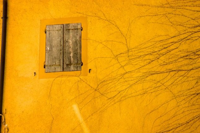 Un volet en bois sur une maison jaune en Italie.