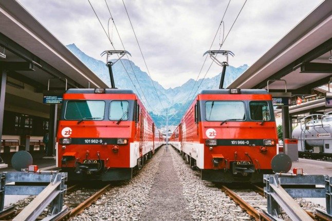 Deux trains côte à côte dans une gare des Alpes suisses.