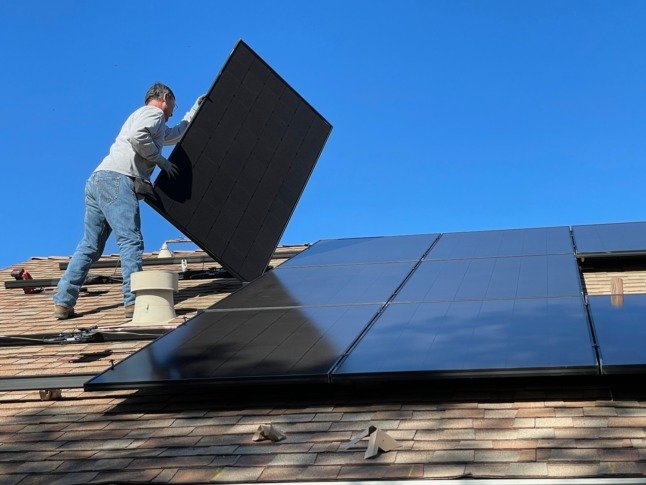 Un ouvrier installe des panneaux solaires sur un toit.