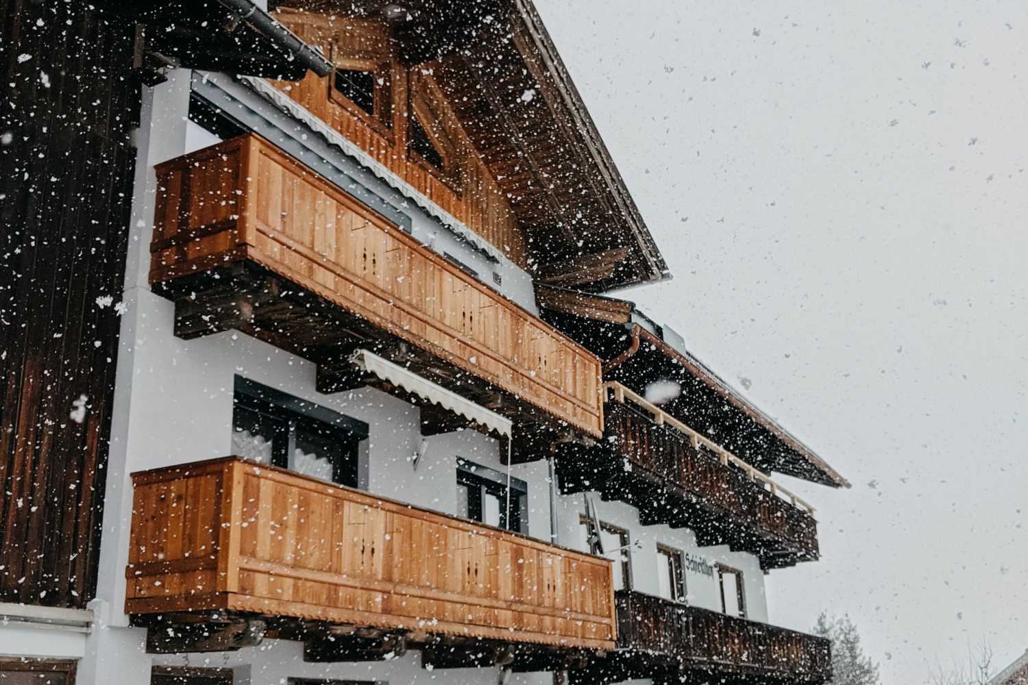 Une maison autrichienne aux panneaux de bois est embrassée par de petits flocons de neige par une journée agréable. Photo par Jara de Pexels