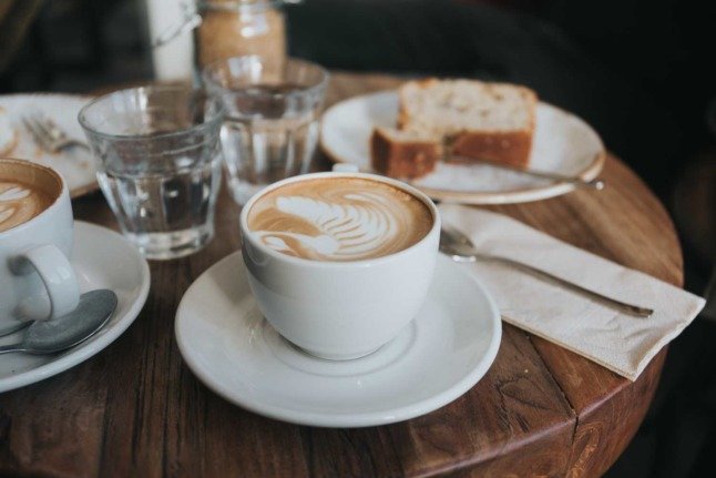 Plusieurs tasses à café sont posées à côté d'une assiette de gâteaux dans un café de Vienne. Photo par Alisa Anton sur Unsplash