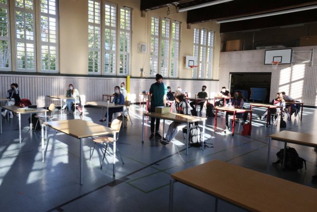 Des élèves masqués sont assis dans une salle de sport réaménagée à Iéna.