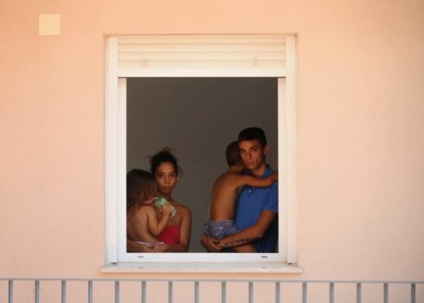 Un jeune couple et ses deux enfants en bas âge à la fenêtre d'un immeuble occupé à Sanlucar de Barrameda, près de Cadix. Photo : AFP PHOTO/ CRISTINA QUICLER