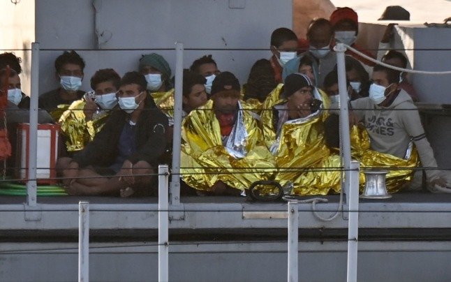 Des migrants réchauffés par des couvertures d'urgence arrivent sur un bateau de l'agence de maintien de l'ordre italienne Guardia Di Finanza, le 17 mai 2021. 