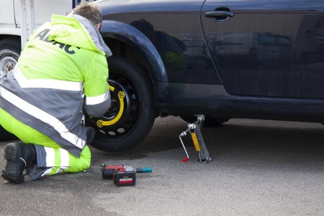 Un mécanicien de l'ADAC en Allemagne répare une voiture avec un pneu crevé