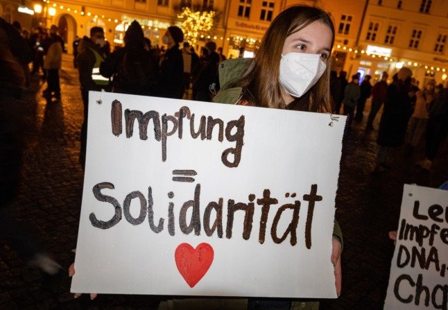 Un manifestant pro-vaccin tient une pancarte indiquant que la vaccination est synonyme de solidarité à Griefswald.