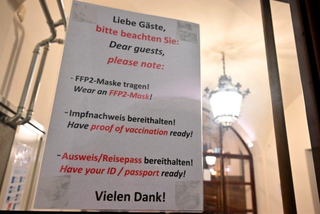 Une maison d'hôtes munichoise avec un panneau demandant aux gens de préparer leur carte de vaccination et leur carte d'identité. 