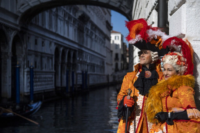 Des fêtards masqués portant des costumes de carnaval traditionnels posent sur la place Saint-Marc pendant le carnaval de Venise le 13 février 2022.