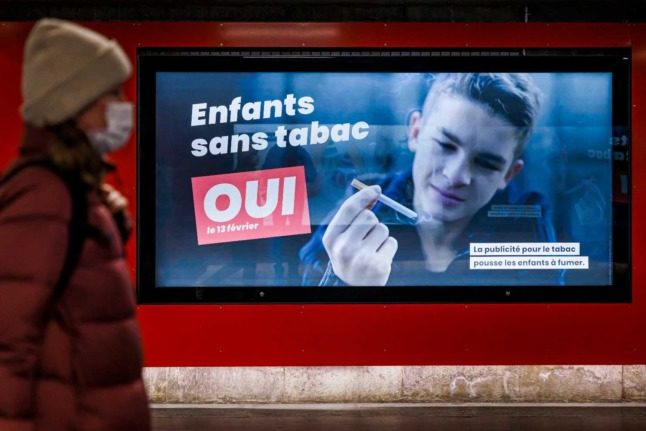 Une affiche de campagne encourage les gens à soutenir le vote contre la publicité sur le tabac, disant en français 