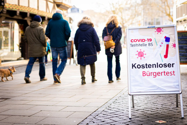 Des personnes passent devant un panneau indiquant une station de test Covid à Braunschweig.