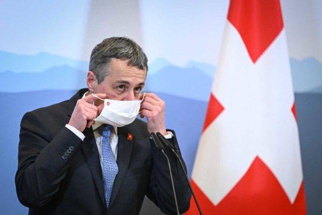 Le président suisse Ignazio Cassis enlève son masque. Photo : Fabrice COFFRINI / AFP