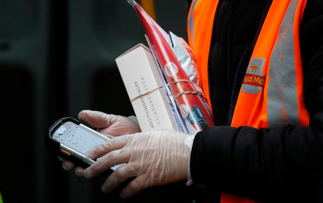 un employé de royal mail transportant des colis