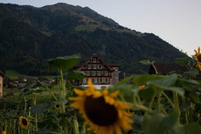 Plusieurs maisons dans la campagne suisse. Photo par Eliabe Costa sur Unsplash