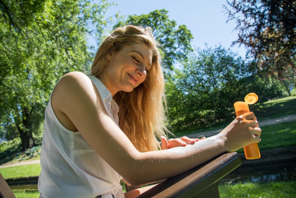 Une femme applique une lotion solaire un jour d'été. 