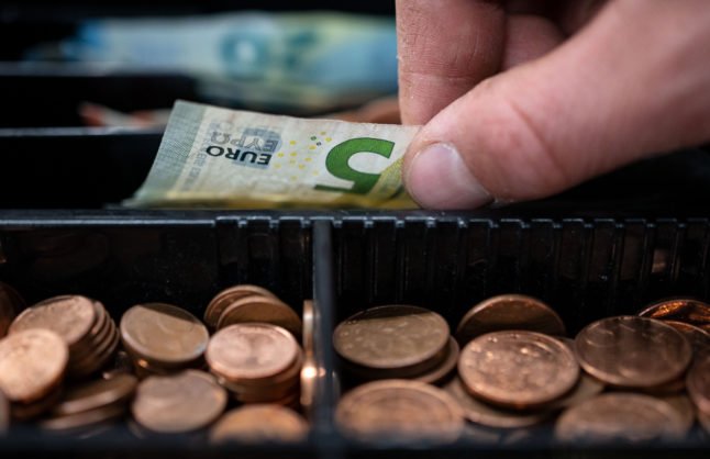 Un employé prend de l'argent à la caisse d'un magasin à Stuttgart.