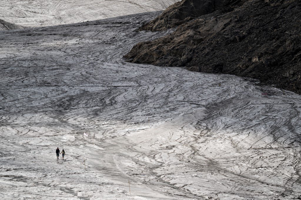 Un couple se tient la main en marchant sur le glacier de Tsanfleuron en fusion au-dessus des Diablerets. 