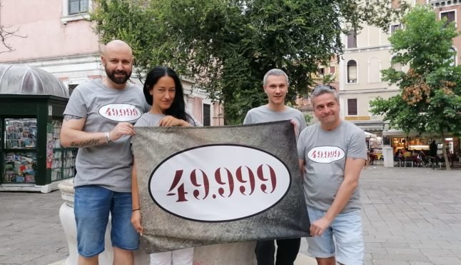 Des militants brandissent une banderole affichant le nombre 49 999, dans le cadre d'une campagne visant à attirer l'attention sur le dépeuplement rapide de Venise. 