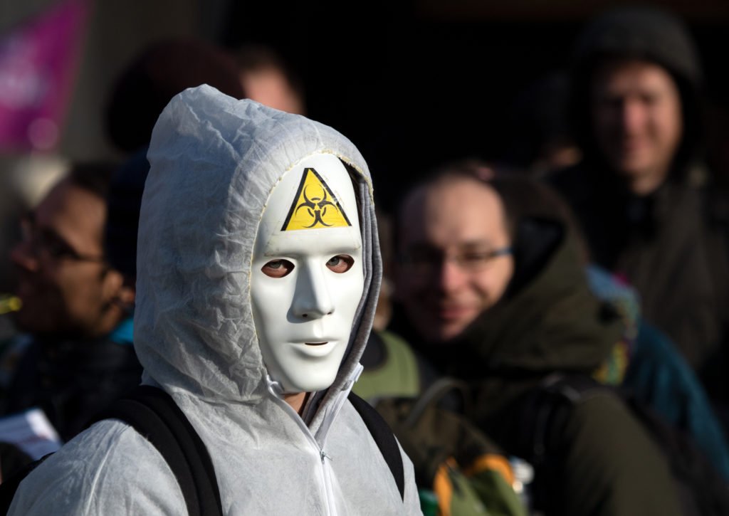 Un manifestant porte un masque blanc avec un autocollant avec le symbole 