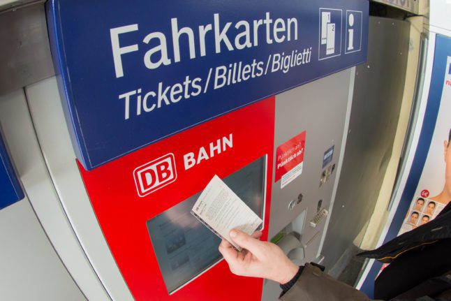 Un passager achète un billet à un distributeur de billets de la DB.