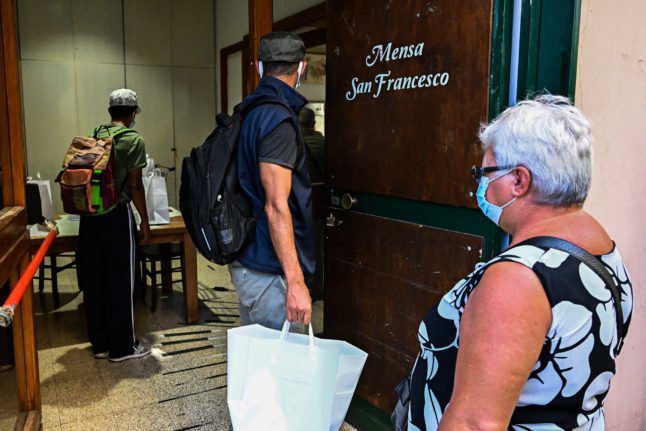 Des gens viennent chercher un sac de nourriture à la soupe populaire San Francesco de Mario Conte, aidée par l'association caritative catholique Caritas, le 20 septembre 2022 à Salerne.