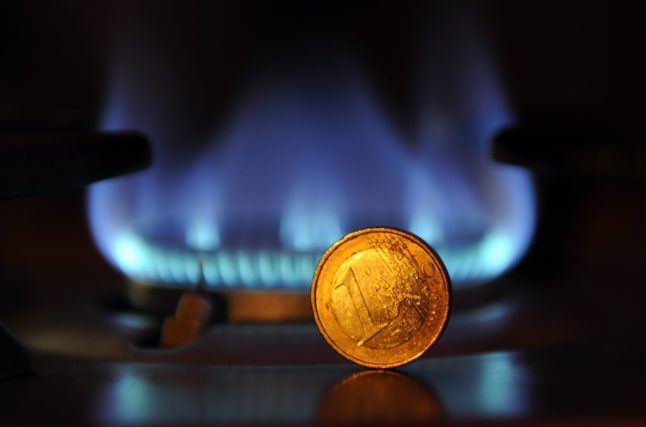 Une pièce d'un euro se dresse devant une flamme sur une cuisinière à gaz.