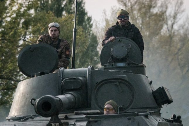 Des soldats ukrainiens montent sur un obusier automoteur.