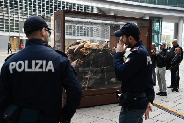La police regarde une exposition contenant les restes de la voiture d'escorte du juge italien Giovanni Falcone, assassiné par la mafia en 1992.